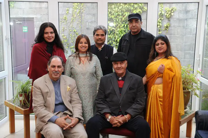 Seven adults pose indoors at Siamsa Tíre, venue hire Tralee, with plants and windows behind them.