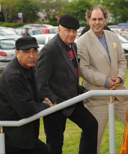 Three older men stand outdoors, chatting about Siamsa Tíre traditional Irish arts performances.