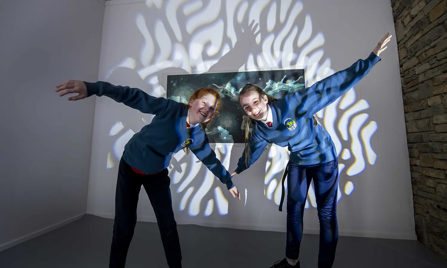 Two girls in uniforms pose playfully under wavy light at the Arts Centre Tralee Kerry.