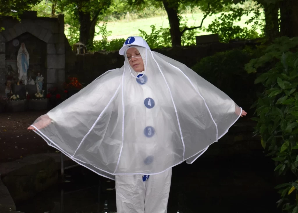 Person in white with transparent cape poses outdoors, evoking Siamsa Tíre traditional Irish arts.