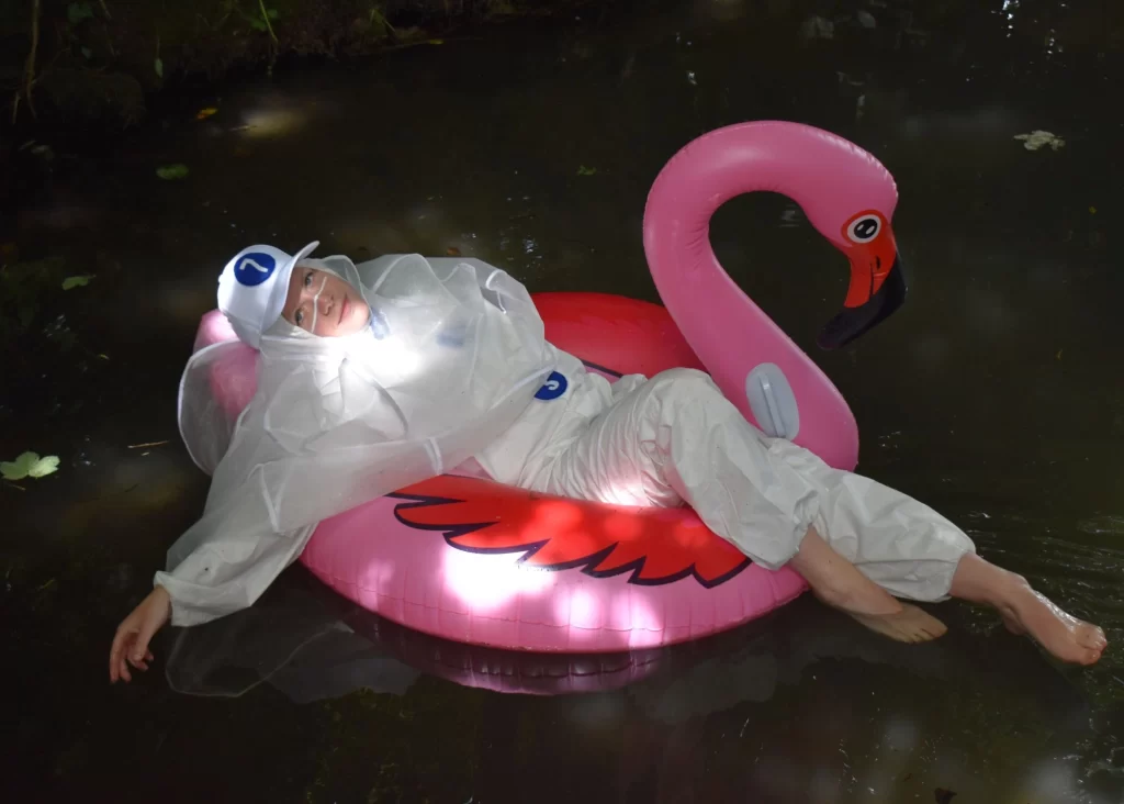 Person in white suit on pink flamingo float, spotlighted—Arts centre Tralee Kerry style.