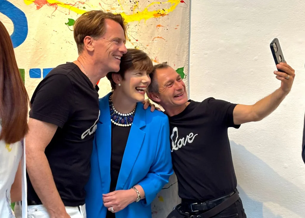 Three smiling people take a selfie at the vibrant Siamsa Tíre theatre Tralee backdrop.