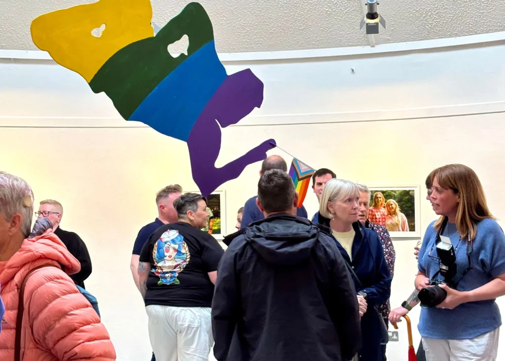People gather in Siamsa Tíre theatre Tralee with pride art and photographs on display.