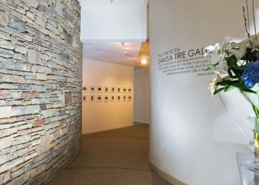 Curved gallery hallway at Siamsa Tíre theatre Tralee with art, stone wall, and flowers.