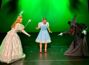 Three women as Wizard of Oz characters on stage at Siamsa Tíre theatre Tralee, green backdrop.