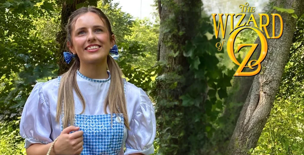 A woman in blue gingham stands by "The Wizard of Oz" logo at Siamsa Tíre theatre Tralee.