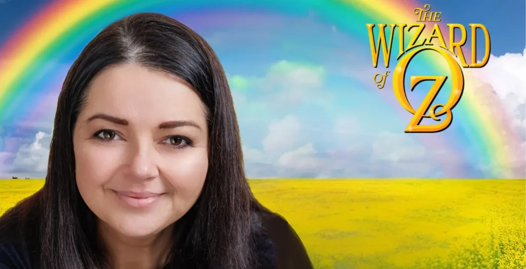 Woman smiling before Wizard of Oz logo at Arts Centre Tralee Kerry, rainbow and yellow field.