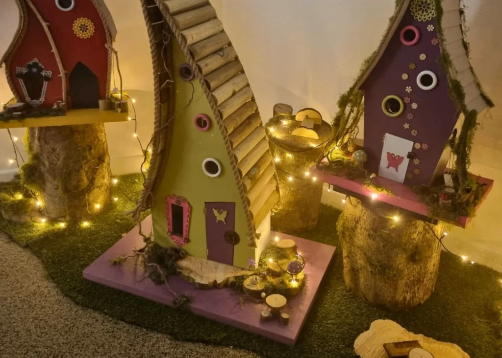 Three whimsical fairy houses on tree stumps, like a scene near Siamsa Tíre theatre Tralee.