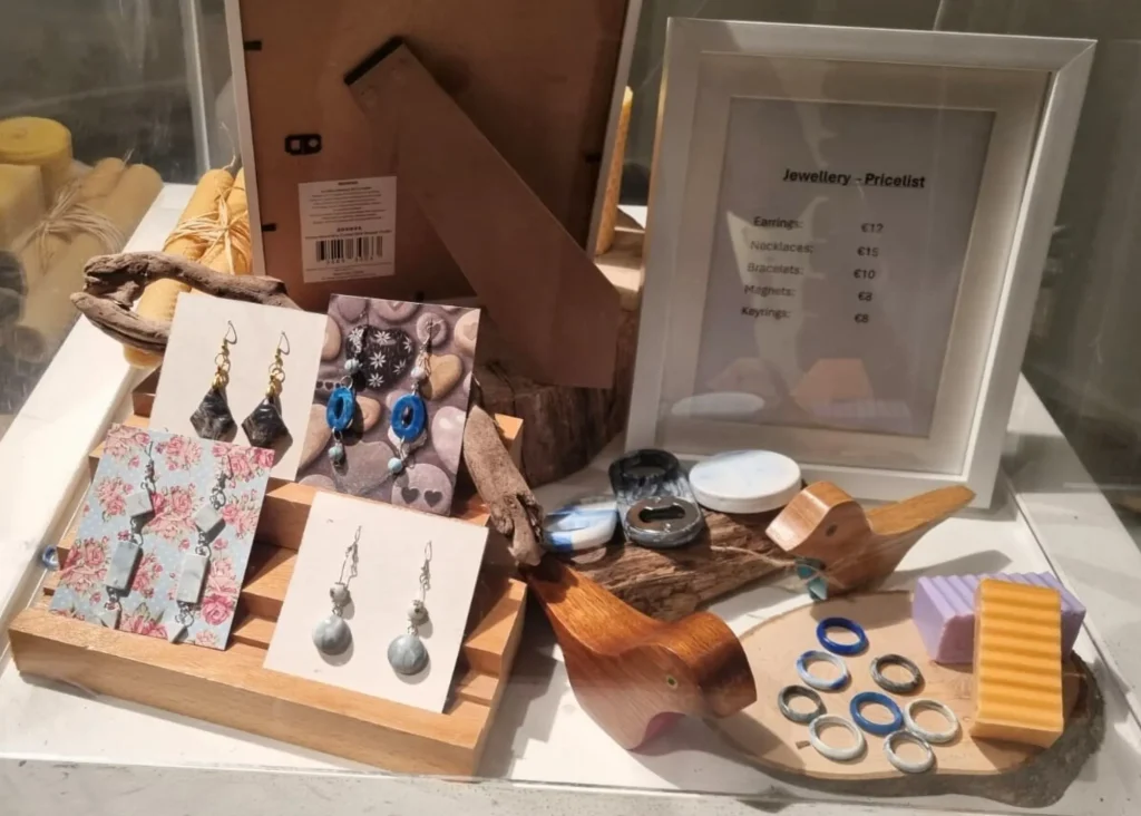 Display of handmade jewelry at Siamsa Tíre theatre Tralee with price list in a white frame.