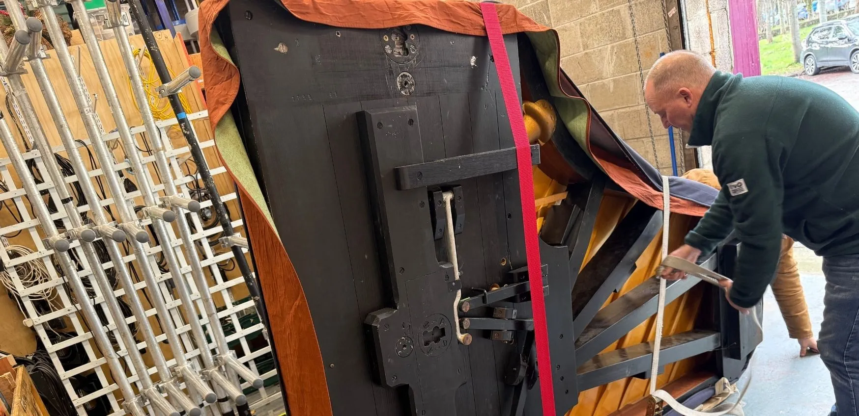 A Man in a warehouse removing a carefully wrapped piano