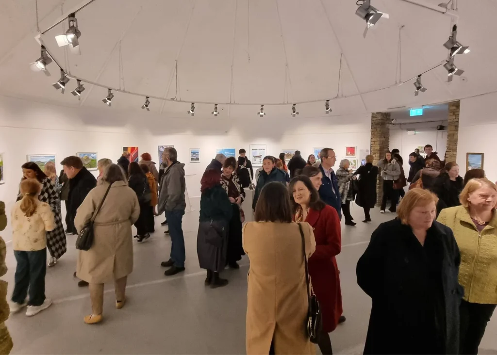 Photo of a crowd of people browsing in an art gallery.