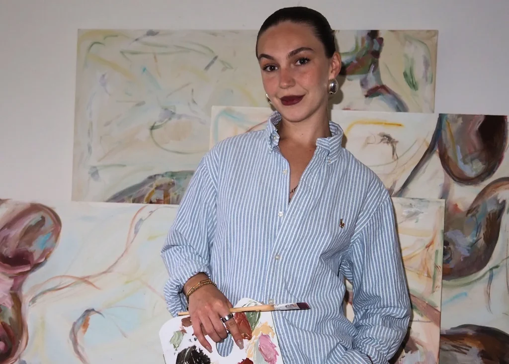 A female artist holding paint and a brush