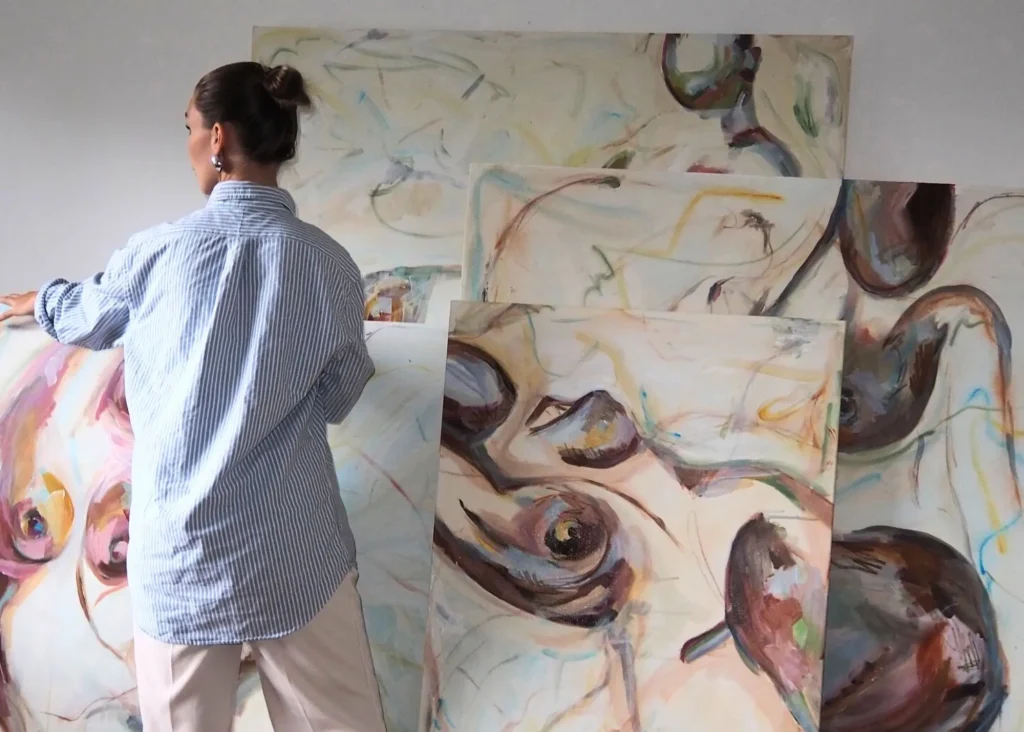 A woman with her back turned holding paintings