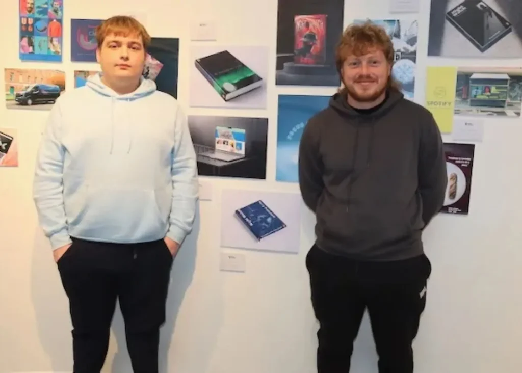 ***Two young men standing in front of art on a wall