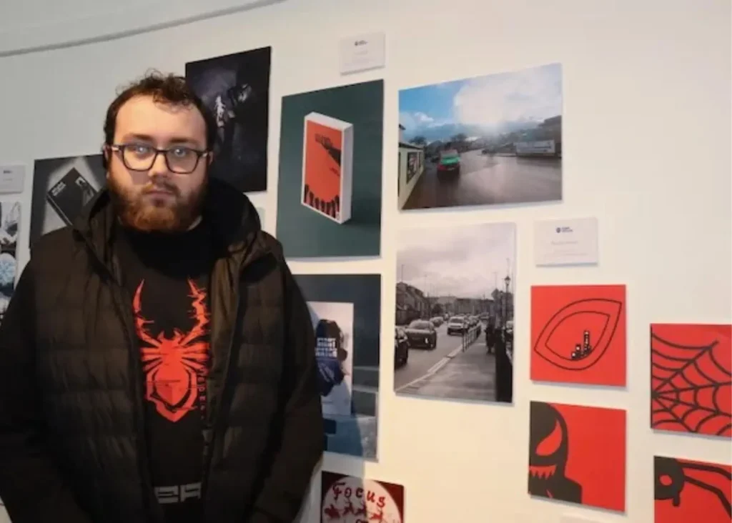 Photo of a man standing in front of art o a wall